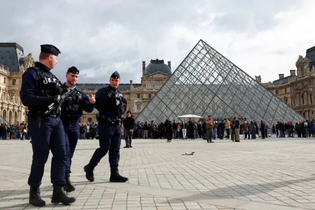 FILE PHOTO: French CRS riot police officers walk near the glass Pyramid of the Louvre Museum, after French police arrested suspects in the Louvre heist case, in Paris, France October 27, 2025. REUTERS/Abdul Saboor/File Photo