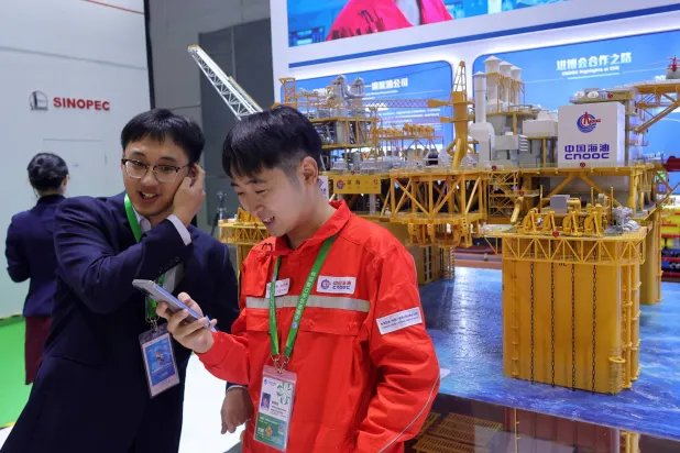 شابان يقفان بجوار نموذج لمنصة بحرية في جناح شركة الصين الوطنية للنفط البحري بمعرض الصين الدولي الثامن للواردات في شنغهاي (رويترز)
