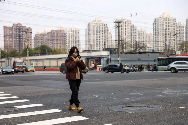 A woman wearing a face mask walks on a street in Beijing, China, 06 November 2025. (EPA)