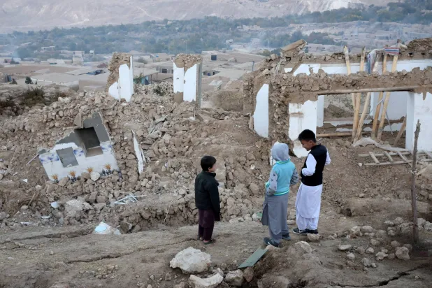 أولاد واقفون بجوار حطام المنازل المتضررة في أعقاب زلزال وقع مؤخراً بمنطقة مرمول في ولاية بلخ بأفغانستان يوم 5 نوفمبر 2025 (رويترز)