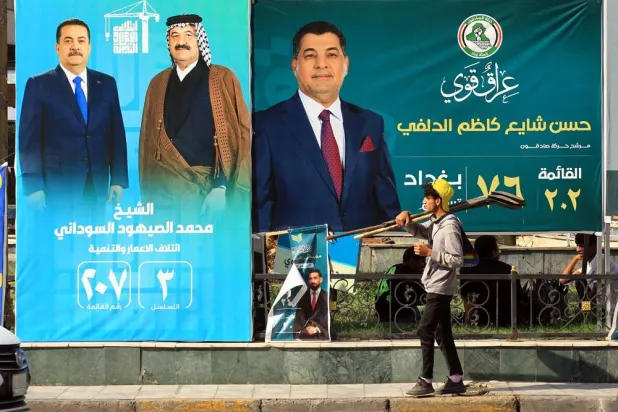 A young Iraqi worker walks past election campaigning posters ahead of the parliamentary elections in Baghdad, Iraq, 07 November 2025. (EPA)