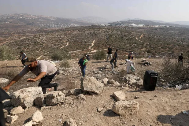 فلسطينيون يفرون من قنابل غاز أطلقها الجيش الإسرائيلي نحوهم بعد احتجاجهم أمس على مصادرة المستوطنين لأراضيهم شرق نابلس بالضفة الغربية المحتلة (أ.ف.ب)