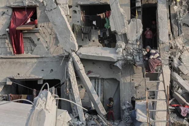 امرأة فلسطينية تجلس على سلم خارج منزلها المتضرر بشدة في جباليا شمال قطاع غزة (أ.ف.ب)