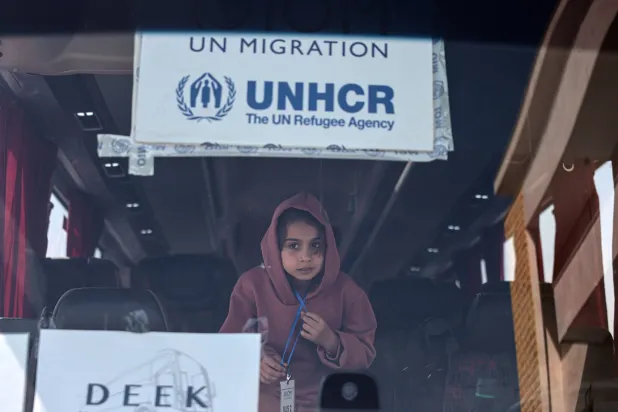 طفلة على متن حافلة تقل لاجئين سوريين خلال رحلة عودتهم من لبنان الخميس الماضي (إ.ب.أ)