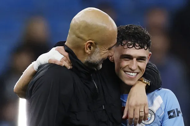 الإسباني بيب غوارديولا يحتفل بالفوز مع لاعبه فيل فودن (رويترز)