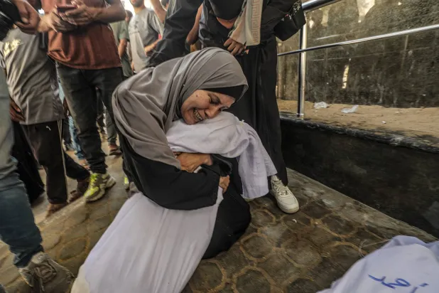 أمٌّ تحتضن جثمان ابنتها في مستشفى «الشفاء» بمدينة غزة (إ.ب.أ)
