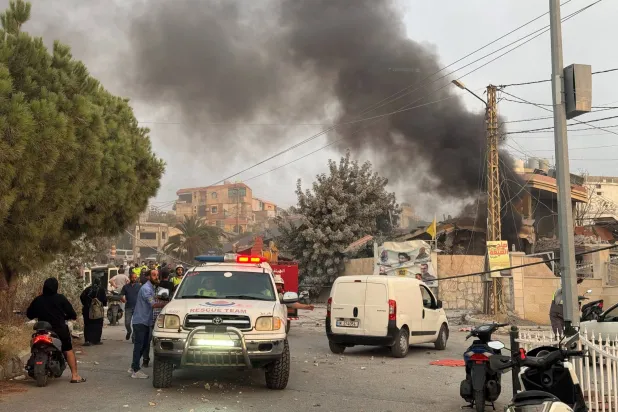 FILE PHOTO: People gather as smoke rises after Israeli strikes following Israeli military's evacuation orders, in Tayr Debba, southern Lebanon November 6, 2025. REUTERS/Ali Hankir/File Photo