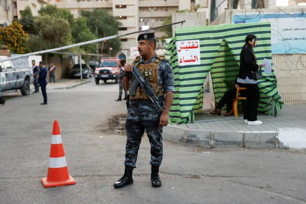 فرد أمن خارج مركز اقتراع بالعراق (رويترز)