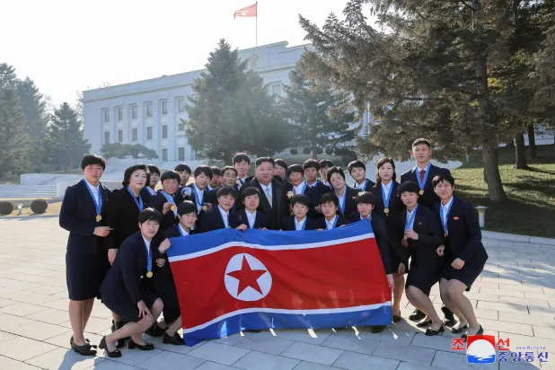 This picture taken on January 2, 2025 and released from North Korea's official Korean Central News Agency (KCNA) via KNS on January 3, 2025 shows North Korea's leader Kim Jong Un (C) posing for a commemorative photo with players and coaches who won the championship at the 2024 U-17 Women's World Cup in November in the Dominican Republic, outside the Party Central Committee headquarters building in Pyongyang. (KCNA via KNS / AFP) 