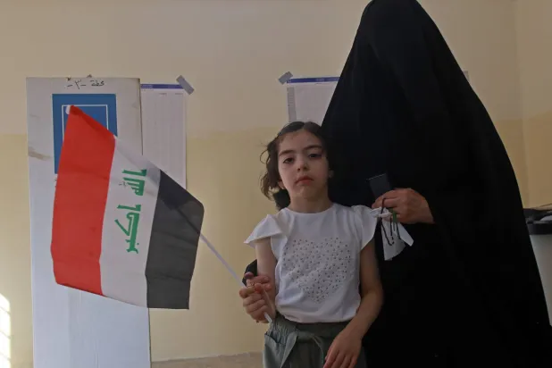 سيدة عراقية مع ابنتها داخل أحد مراكز الاقتراع في الانتخابات البرلمانية اليوم (إ.ب.أ)