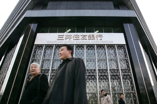 مارّة أمام المقر الرئيسي لبنك «سوميتومو ميتسوي» في العاصمة اليابانية طوكيو (رويترز)