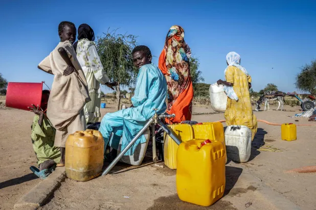 لاجئون سودانيون يملأون عبوات بالمياه داخل مخيم تيني المؤقت في تشاد يوم الاثنين (أ.ف.ب)