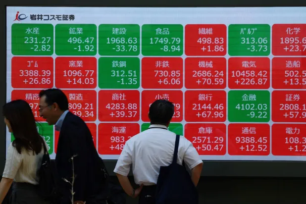 رجل يتفحص لوحة إلكترونية تعرض أداء مؤشر نيكي خارج أحد مكاتب الوساطة بطوكيو (رويترز)
