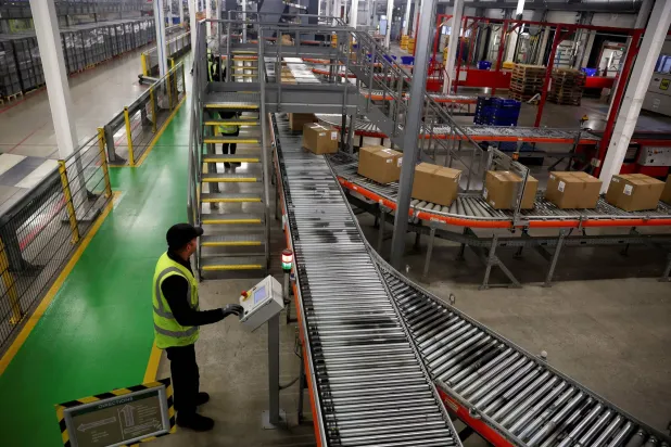 An employee oversees packages being transported on a conveyor belt through the automated sorting facility at a Marks & Spencer (M&S) distribution center in Castle Donington, Leicestershire, Britain, November 7, 2025. REUTERS/Temilade Adelaja