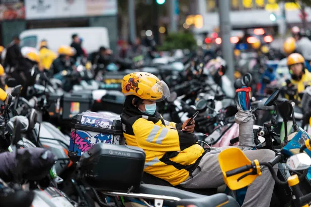 عمال توصيل على دراجات نارية بانتظار تجهيز الطلبات وتوصيلها في «يوم العزاب» بمدينة شنغهاي (إ.ب.أ)