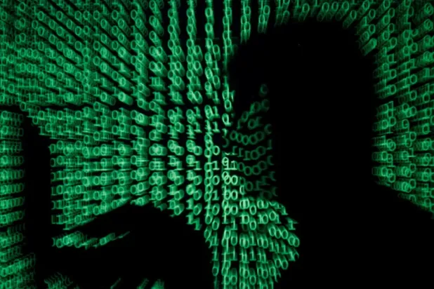 A man holds a laptop computer as cyber code is projected on him in this illustration picture taken on May 13, 2017. (Reuters)
