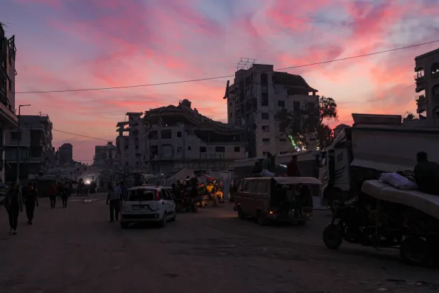 فلسطينيون يسيرون بالقرب من مبانٍ مدمرة في مدينة غزة وسط وقف إطلاق نار بين إسرائيل و«حماس» (إ.ب.أ)