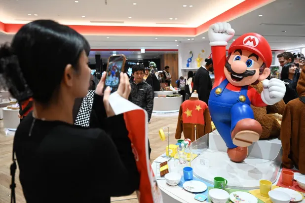 A woman takes photos of a Super Mario figure at the Nintendo Tokyo store in Tokyo on November 4, 2025. (Photo by GREG BAKER / AFP)