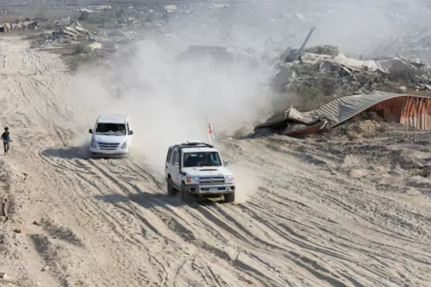 A Red Cross vehicle, escorted by a van driven by a Hamas militant, moves in an area within the so-called "yellow line" to which Israeli troops withdrew under the ceasefire, as Hamas says it continues to search for the bodies of deceased hostages seized during the October 7, 2023, attack on Israel, in Gaza City November 12, 2025 - Reuters 