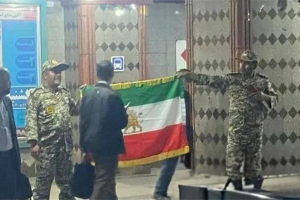 الرجلان وهما يلوّحان بعلم يحمل شعار «الأسد والشمس» المرتبط بنظام الشاه السابق (وكالة فارس)