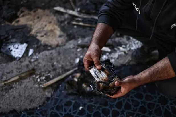 A Palestinian holds burnt Qur’an pages after a settler attack on Hajjah Hamidah mosque  in the village of Istiya, near Salfit, in the occupied West Bank (AFP)