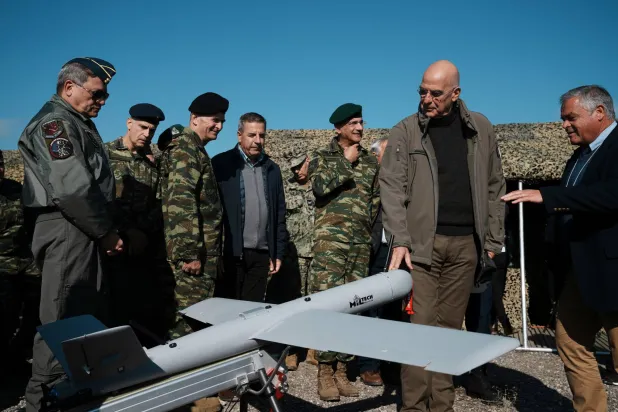 وزير الدفاع اليوناني نيكولاوس ديندياس (الثاني من اليمين) يلمس طائرة من دون طيار خلال مناورة بالذخيرة الحية بالقرب من مدينة ألكسندروبوليس في شمال شرق البلاد (أ.ب)