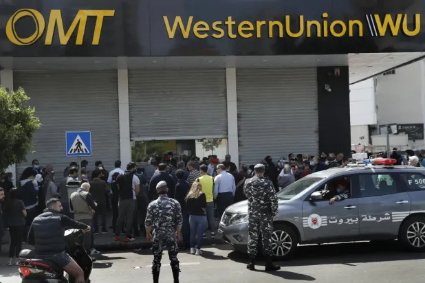 Lebanese citizens queue outside a Western Union shop to receive their money transfers. AP file photo
