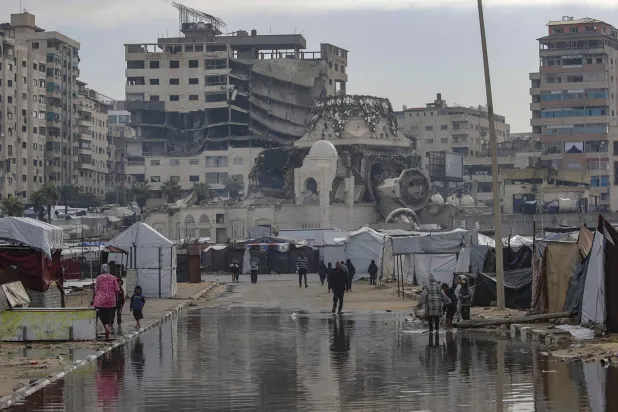 نازحون فلسطينيون فاقمت الأمطار معاناتهم في مخيمهم وسط الخراب بميناء غزة أمس (إ.ب .أ)