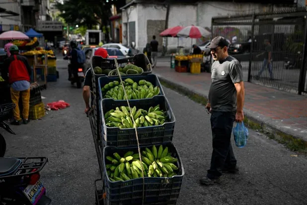  A man pushes a hand truck loaded with plantains through La Candelaria neighborhood in Caracas on November 13, 2025. (AFP) 