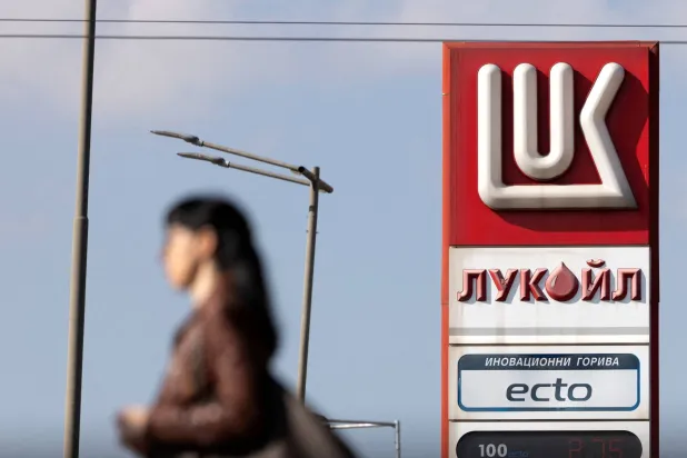 امرأة تمشي بالقرب من محطة وقود تابعة لشركة «لوك أويل» في صوفيا (رويترز)