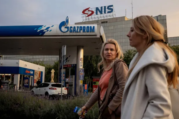 أشخاص يمرون أمام محطة وقود تابعة لـ«غازبروم نفط» الروسية المساهم الرئيس في «إن آي إس» الصربية في بلغراد (رويترز)