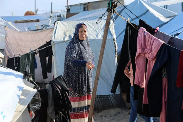 سيدة فلسطينية تقف وسط الخيم المتضررة من مياه الأمطار في خان يونس بغزة (رويترز)