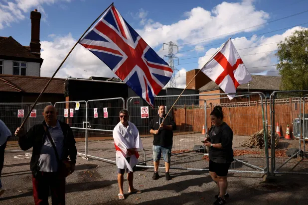 FILE PHOTO: Protesters hold the Union Jack and St George's flags outside the Bell Hotel in Essex after the British government challenged a court ruling requiring asylum seekers to be temporarily evicted from the hotel in Epping, Britain, August 29, 2025. REUTERS/Jack Taylor/File Photo