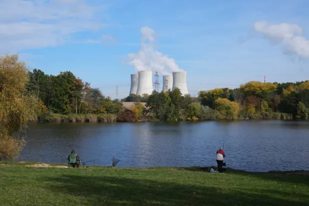 أشخاص يصطادون بالقرب من محطة دوكوفاني للطاقة النووية الشاهقة -في الخلفية- في دوكوفاني (أ.ب)