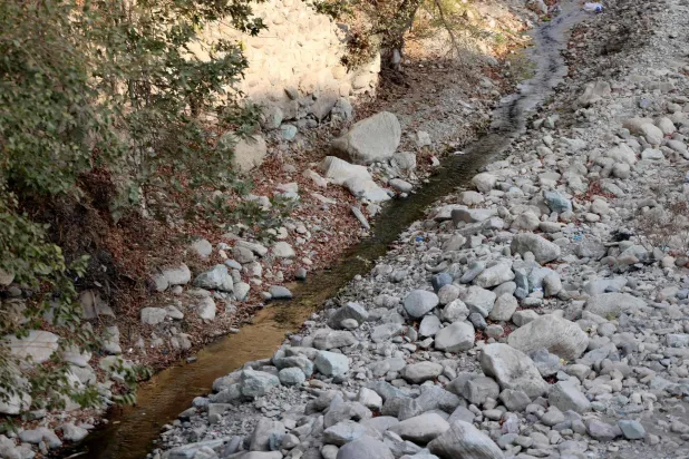 A trickle of water flows in the mainly dried-up Kan River, west of Tehran on November 9, 2025. (Photo by ATTA KENARE / AFP)