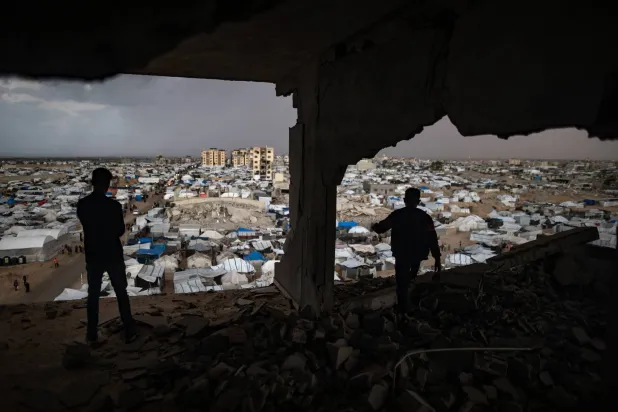 فلسطينيان يقفان داخل مبنى مدمر بسبب الحرب في خان يونس جنوب قطاع غزة (إ.ب.أ)