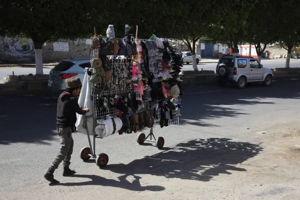 بائع متجول في صنعاء يبحث عن زبائن حيث يعرض قبعات شتوية وحقائب كتف وإكسسوارات (إ.ب.أ)