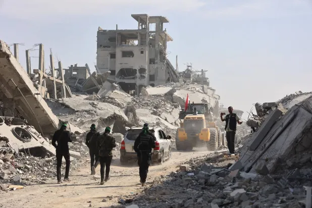 عناصر من «حماس» برفقة أعضاء من الصليب الأحمر الدولي يتبعون حفاراً بحثاً عن جثث الرهائن الإسرائيليين في غزة (أ.ف.ب)