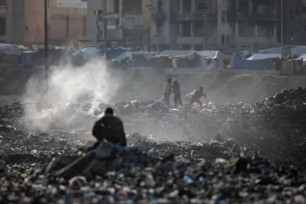 Filistinliler, Gazze Şeridi’nin güneyindeki Han Yunus'taki binaların molozları arasından plastik atık topluyor (EPA)