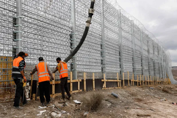Israeli workers pour concrete while working on the border fence separating northern Israel from southern Lebanon on November 16, 2025. (AFP)