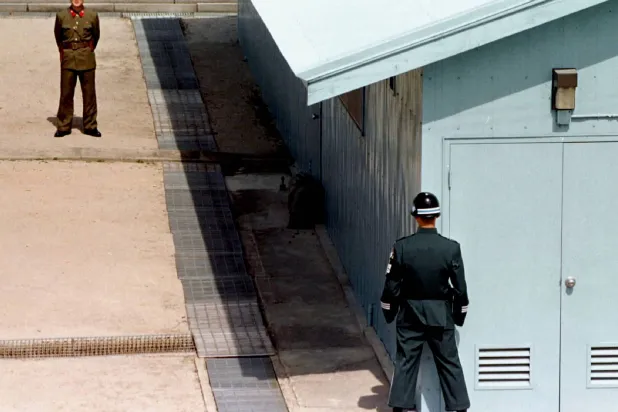 جندي من كوريا الشمالية يقف في مواجهة جندي من كوريا الجنوبية عند خط ترسيم الحدود بين البلدين (أرشيفية - رويترز)