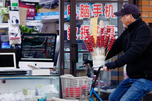 رجل يمر أمام متجر لبيع الإلكترونيات بمدينة شنغهاي الصينية (إ.ب.أ)