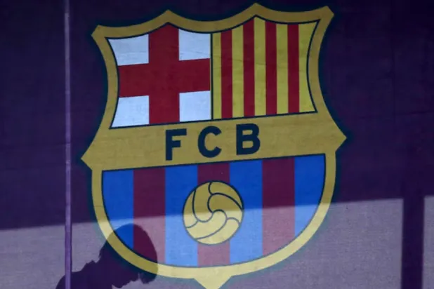 A silhouette of a woman walks past behind a FC Barcelona's logo at Camp Nou stadium in Barcelona, Spain, March 24, 2016. REUTERS/Albert Gea/File Photo 