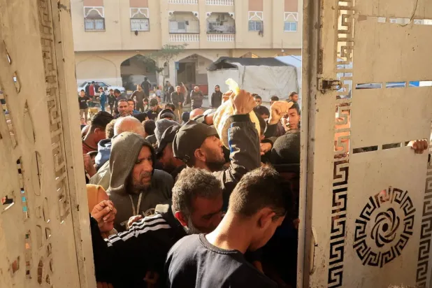 Filistinliler Pazartesi günü Gazze Şeridi'nin güneyindeki Han Yunus'ta bir dağıtım noktasından ekmek almak için bekliyor (Reuters)