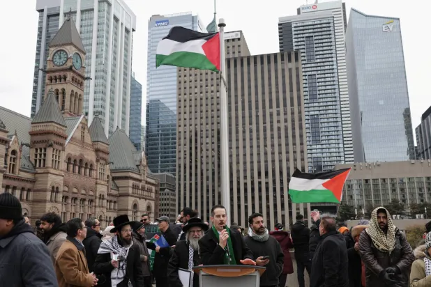 رجل يتحدث أثناء تجمع الناس دعماً للفلسطينيين بينما يرفرف العلم الفلسطيني في تورونتو بكندا 17 نوفمبر 2025 (رويترز) 