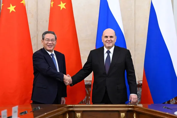 رئيس الوزراء الروسي ميخائيل ميشوستين (يمين) يصافح نظيره الصيني لي تشيانغ (إ.ب.أ)