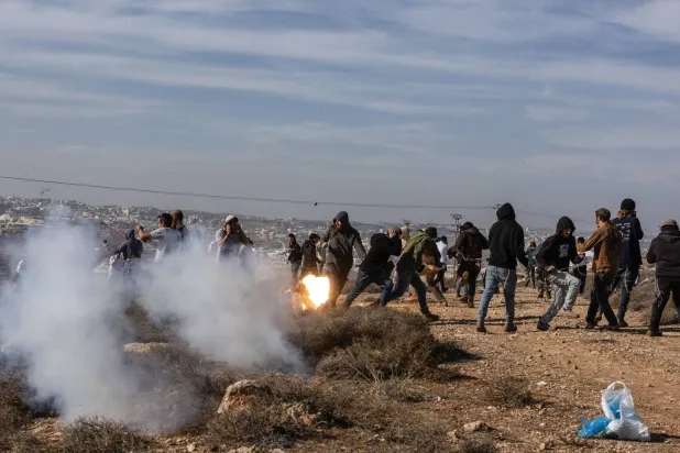 Hilltop Youth run for cover as they clash with Israeli security forces evacuating and demolishing an illegal outpost built near the Jewish settlement of Metzad east in the occupied West Bank, on November 17, 2025. (AFP)