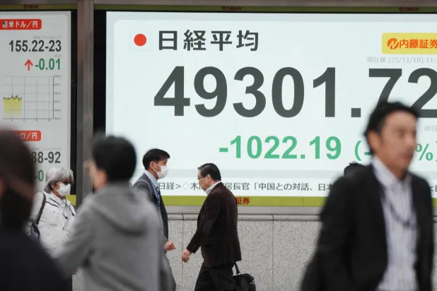 مشاة يمرون أمام شاشة إلكترونية تعرض حركة الأسهم في وسط العاصمة اليابانية طوكيو (أ.ف.ب)