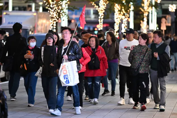 A Chinese tour group walks in the Ginza shopping district in Tokyo on November 17, 2025. (AFP)