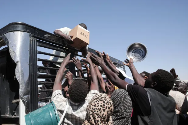 Sudanese families displaced from El-Fasher reach out as aid workers distribute food supplies at the newly established El-Afadh camp in Al Dabbah, in Sudan's Northern State, Sunday, Nov. 16, 2025. (AP Photo/Marwan Ali)